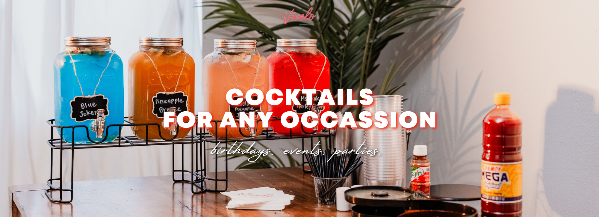 Assorted colorful cocktails in glass dispenser jars that showcases with some of the cocktail items that come with our catering package. 